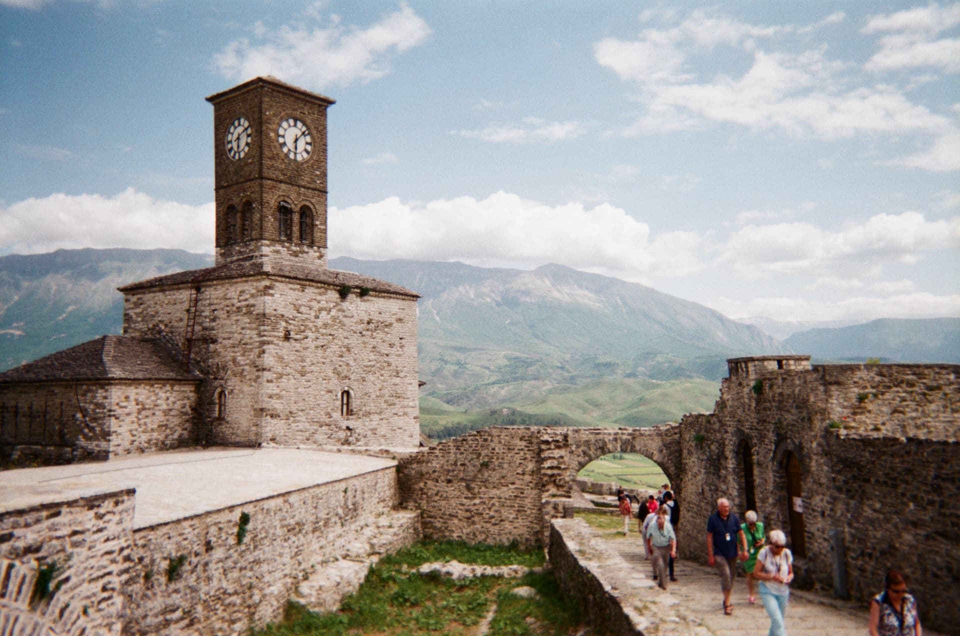 A stone clock tower in a hilltop fortress with mountains behind